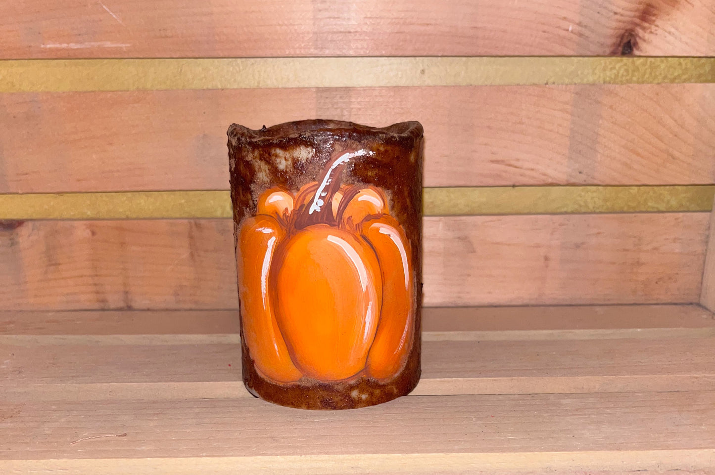 Hand-painted pumpkin on primitive grungy battery-operated candle with rustic cinnamon and coffee finish, perfect for fall farmhouse decor.