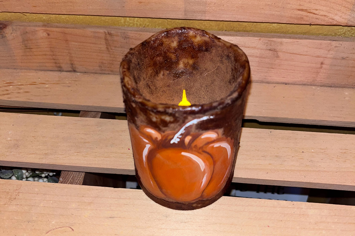Primitive-style battery-operated flameless candle glowing softly, featuring a hand-painted pumpkin and grungy textured finish made with cinnamon and coffee.