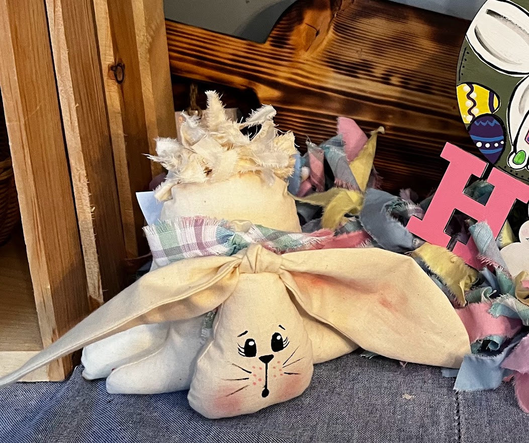 Closer look of the three body parts of muslin fabric stuffed bunny with hand-painted face, three body tiers, floppy ears and rag tail