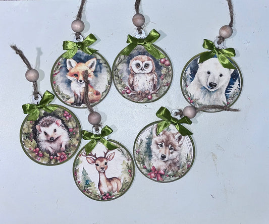 Set of six woodland Christmas ornaments on wooden rounds featuring a deer, fox, bunny, owl, hedgehog, and squirrel decorated with winter greenery, red ribbon hangers, gingham bows, and wood beads.