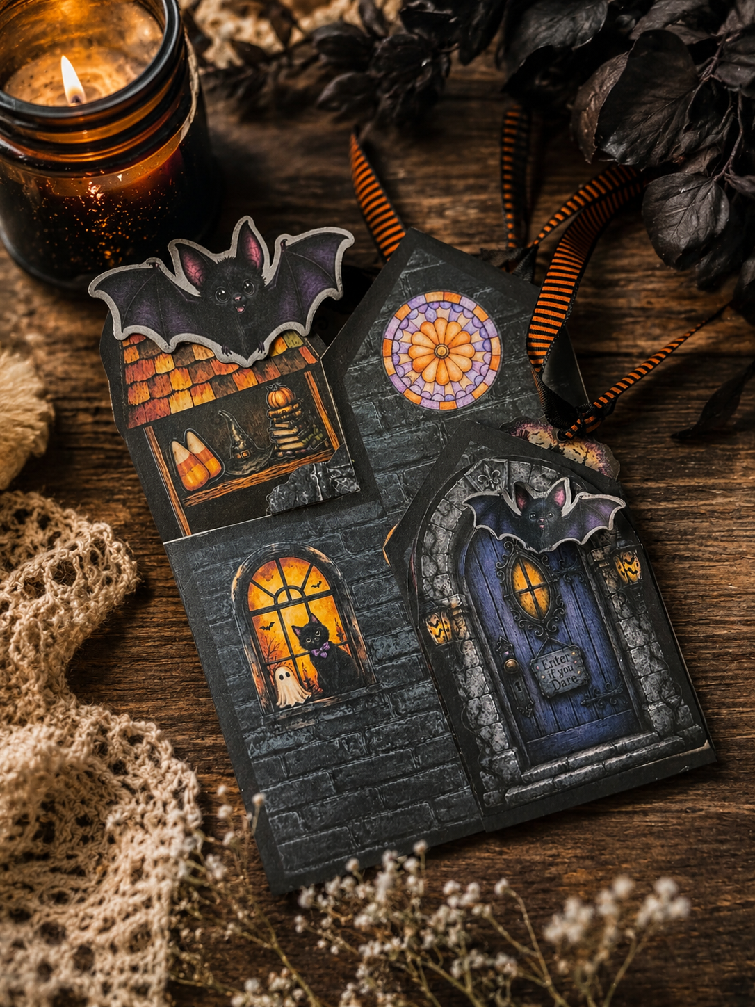Howl-O-Ween Manor Halloween folio displayed on a rustic table with bat embellishments, gothic doors, stained-glass windows, ribbon ties, and a glowing candle.
