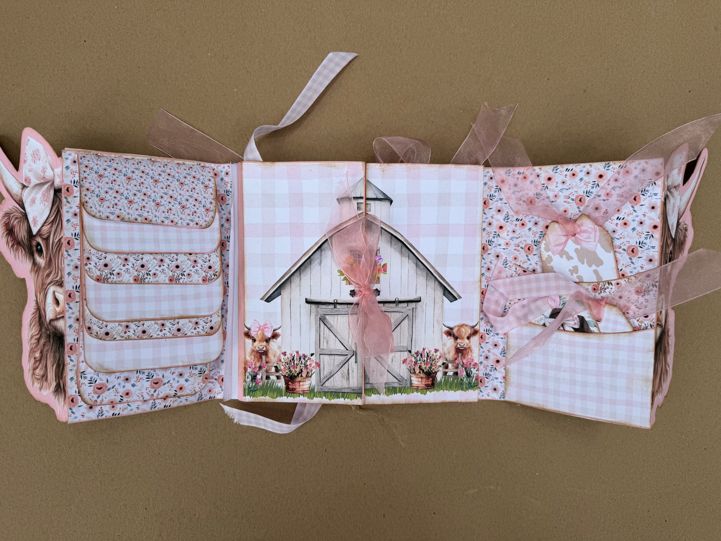 Farmhouse junk journal spread with white barn, Highland cows, floral pockets, and ribbon tags