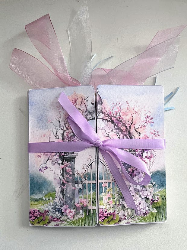 Le’ Gated Garden flip out folio closed view with pastel floral garden gate cover and lavender ribbon bow.