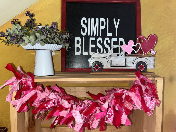 5 different strips of fabrics in reds and pinks with the feature fabric having hearts tied into a garland that can be hung from its loops or nestled in your decor pieces.