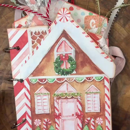 20-second flip-through video of the handmade "Gingerbread Dreams" Christmas junk journal folio. The video shows the gingerbread house–shaped cover with festive ribbons, then flips through decorated inside pages featuring gingerbread men, candy canes, pockets, journaling cards, and Christmas-themed embellishments.