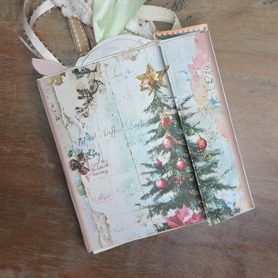 Flip-through video of a handmade Nutcracker-themed Christmas junk journal folio. The video shows the vintage-style cover with a nutcracker soldier and Christmas tree, then opens to decorated pages filled with nutcrackers, ballerinas, ornaments, tags, journaling cards, and pastel holiday embellishments tied with lace and ribbon.