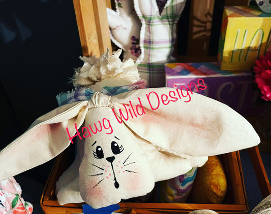 Close up view of muslin stuffed bunny with hand-painted face, three body tiers, floppy ears and rag tail